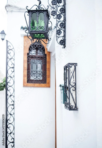 Fototapeta Elegant street scene featuring a vintage lantern and decorative wrought iron details against a pristine white wall, showcasing architectural beauty and charm in a tranquil setting