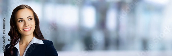 Fototapeta Banner wide image - happy smiling confident cute businesswoman looking gazing upward. Business woman, executive, employee, bank manager, stand against blurred office background with free ad text space