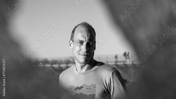 Fototapeta Black And White Portrait Of A Smiling Middle Aged Man Outdoors: Natural Light Photography With Casual Expression And Minimalistic Background