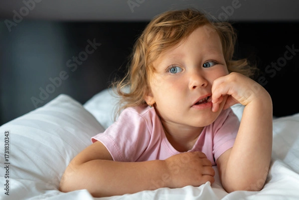 Obraz Little girl lying on bed and biting her fingernails
