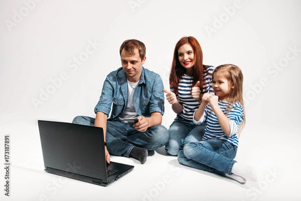 Fototapeta Happy family Father, mother and child lying on the floor with laptop credit card on white background isolated