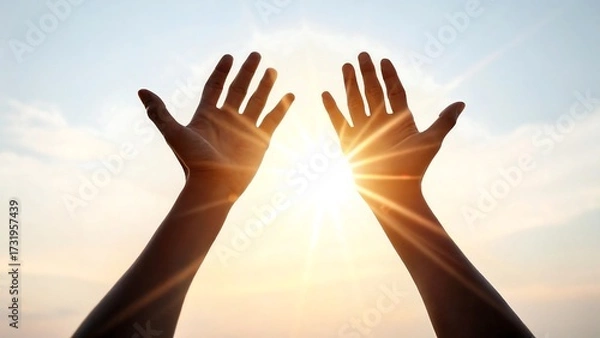 Fototapeta Hands raised toward bright sunlight with glowing rays and warm sky background 
