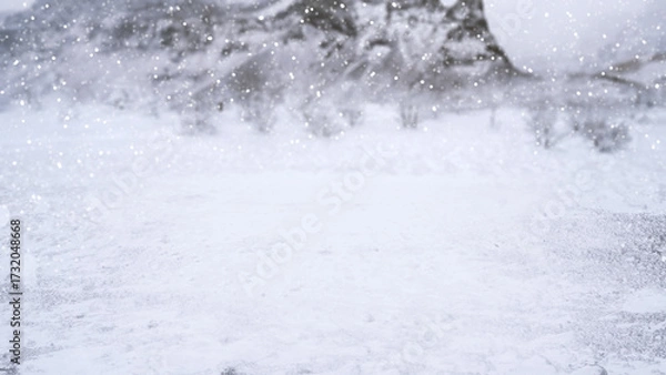 Fototapeta Winter scene with snowfall descending upon a snowy field and covering the ground and trees. Seasonal design or holiday themes for winter