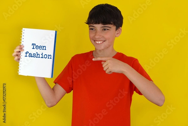 Fototapeta adolescence and fashion concepts. smiling preteen boy pointing to a notebook