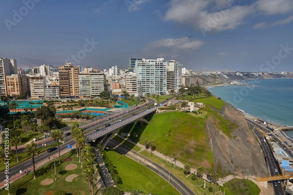 Fototapeta The thrill of paragliding over the stunning coastline of Miraflores is unmatched. With the ocean breeze at your back and the cityscape below.