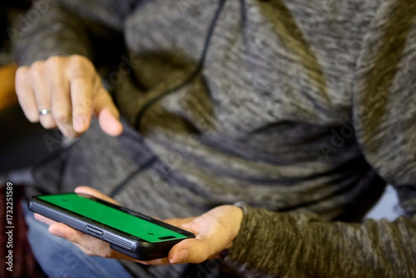 Fototapeta Closeup of man in hoodie browsing smartphone