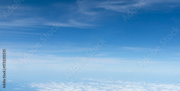 Fototapeta Beautiful landscape view trough window of airplane and cloudless sundown sky behind window of aircraft during flight. blue sky. Flying in the sky and the sea of clouds.