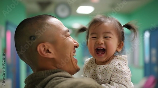 Fototapeta A joyful moment shared between a father and his laughing daughter in a colorful indoor setting.