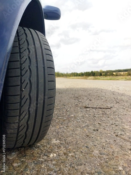 Obraz Close-up view of a car tire on a gravel road in daylight