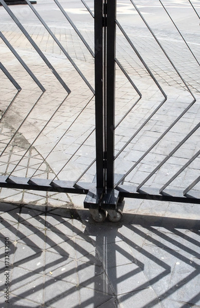 Fototapeta Abstract shadow pattern of metal grid cast on beige wall by sunlight.