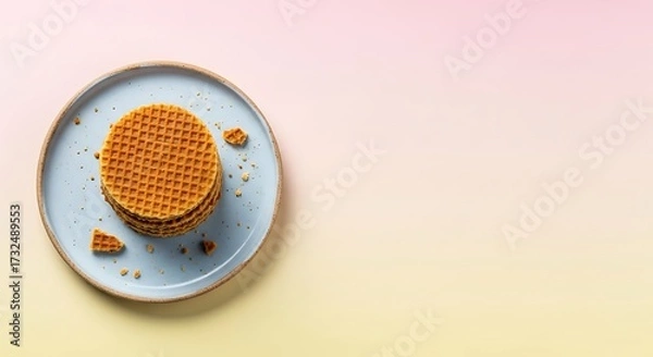 Fototapeta Stack of Round Waffles on Blue Plate with Crumbs on Pastel Pink and Yellow Background