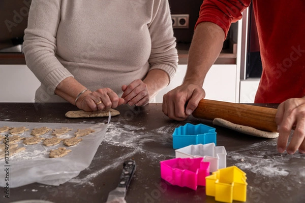 Fototapeta Unrecognizable family cutting cookies with christmas tree shape
