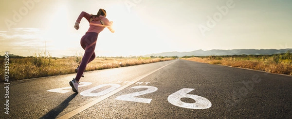 Fototapeta New year 2026 or start straight concept.word 2026 written on the asphalt road and athlete woman runner stretching leg preparing for new year at sunset.Concept of challenge or career path and change.
