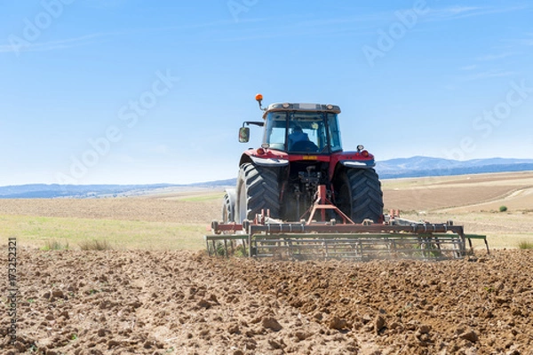 Obraz agricultural tractor in the foreground with blue sky background.