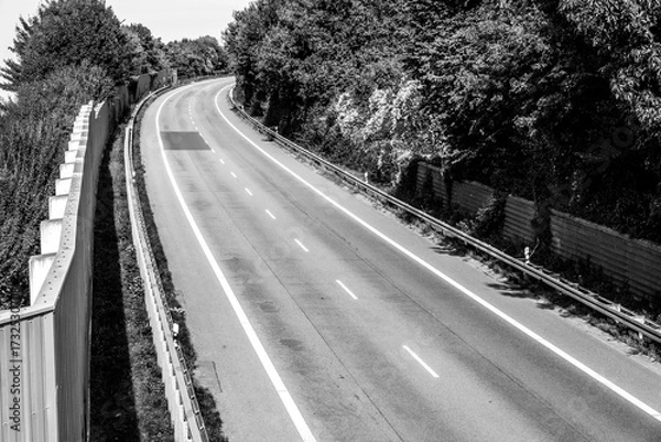 Fototapeta Curved road surrounded by greenery on a clear day near a quiet area perfect for a peaceful drive