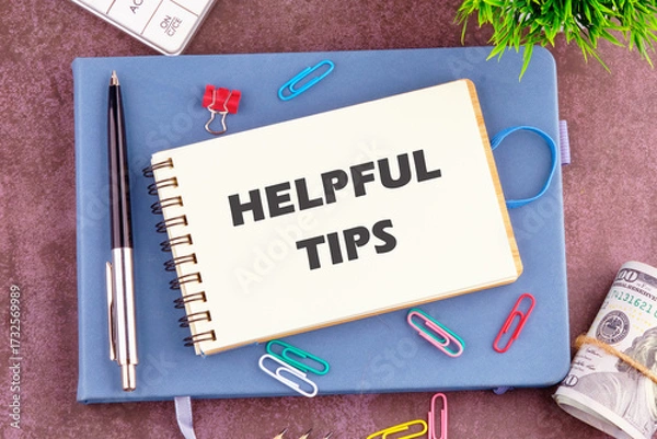 Fototapeta Helpful Tips words in a notebook in a composition with office supplies, top view
