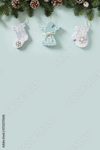 Fototapeta Christmas frame with evergreen branches and angel of wooden natural materials, snowflakes on white background. Copy space. Xmas vertical greeting card. View from above.