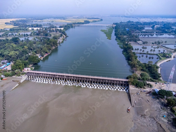 Fototapeta Aerial view of a water barrage with open gates and flowing water. 
The Muhuri Project, officially known as the Muhuri Irrigation Project (MIP), is a major water resource initiative in Bangladesh.