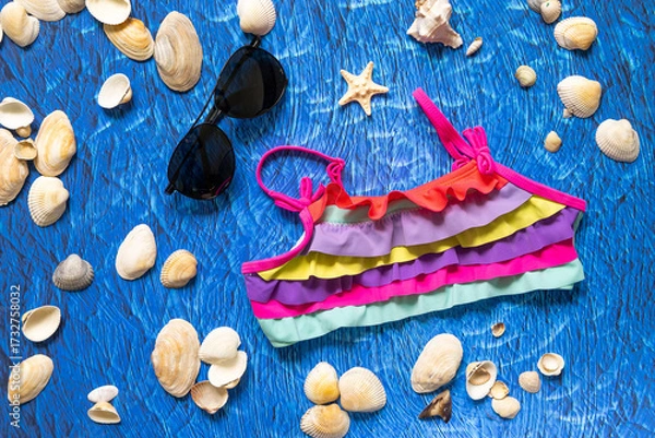 Obraz accesories for summer sea beach on blue wawes background. Beach things sunglasses and swim suit
