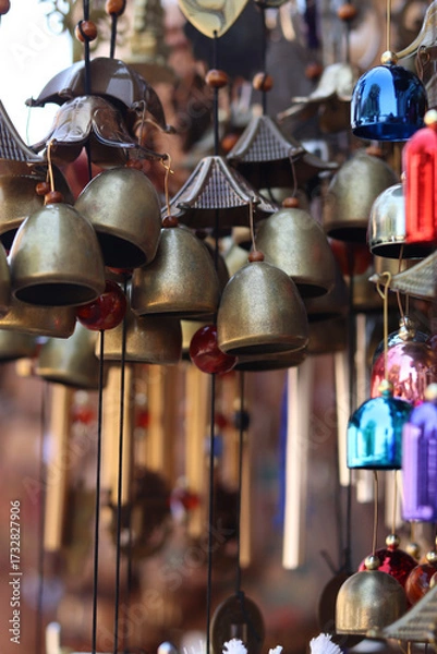 Fototapeta Souvenirs in the form of hanging golden bells, close-up. Souvenir market. Hanging bells used for home decoration. Group of bells with selective focus