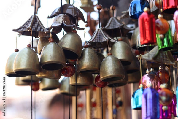 Fototapeta Souvenirs in the form of hanging golden bells, close-up. Souvenir market. Hanging bells used for home decoration. Group of bells with selective focus