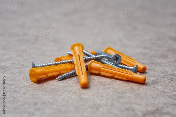 Fototapeta Set of orange plastic dowels and silver metal screws laying on wooden surface. Essential hardware fasteners for mounting and installing.