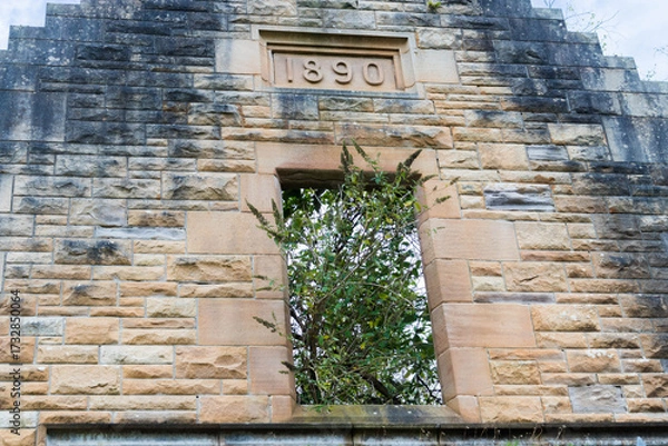 Fototapeta Window opening on abandoned building made of sandstone with engraved year 1890