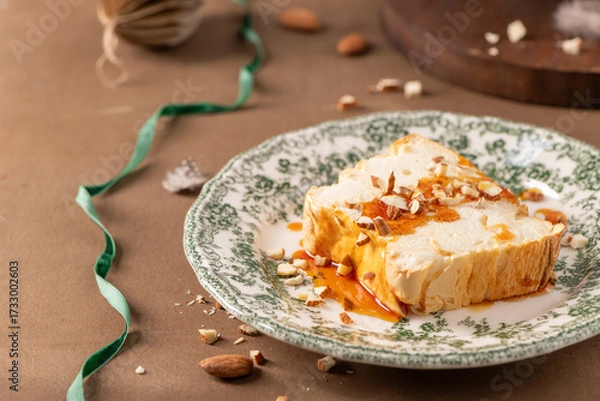 Obraz A slightly elevated shot captures a slice of traditional caramelized egg white pudding known as molotof or molotov, generously drizzled with golden syrup and sprinkled with almond pieces