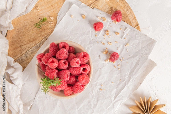 Obraz Two glasses of layered raspberry and chia seed pudding topped with fresh raspberries and white crowberry on a rustic wooden platter