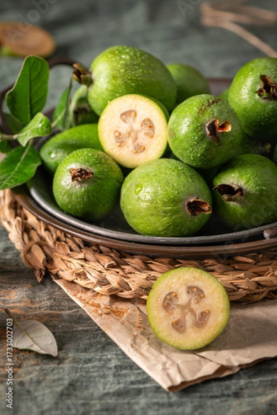 Obraz A rustic still life with ripe pineapple guavas, some cut open to reveal the fleshy pulp, on a small plate and in a basket