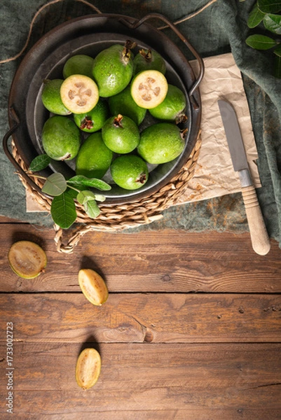 Obraz Overhead shot of a rustic still life with ripe pineapple guavas, some cut open to reveal the fleshy pulp, on a small plate and in a basket