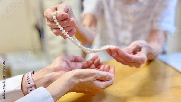 Obraz 高齢女性がパールネックレスを渡す女性の手