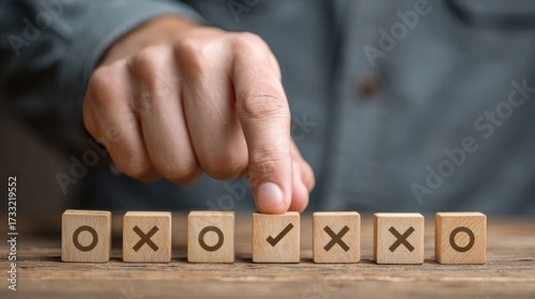 Fototapeta A hand placing a wooden block with a checkmark on a row of blocks with various symbols.