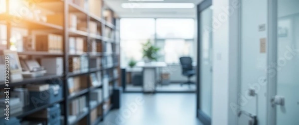 Fototapeta Softly blurred modern office interior with organized bookshelves and a brightly lit distant workspace