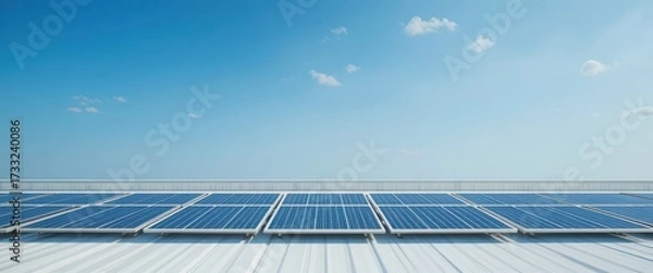 Fototapeta Rows of blue solar panels installed on a white corrugated metal roof under a bright blue sky with scattered clouds
