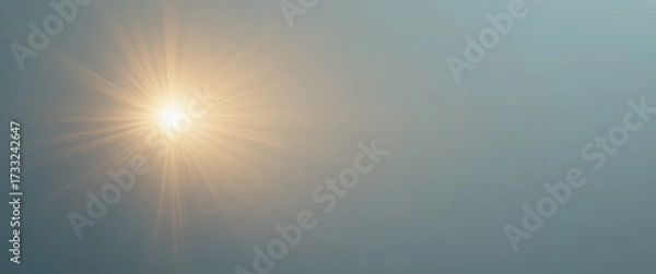 Fototapeta Vibrant starburst light effect emitting bright yellow and orange rays across a serene blue grey gradient sky background