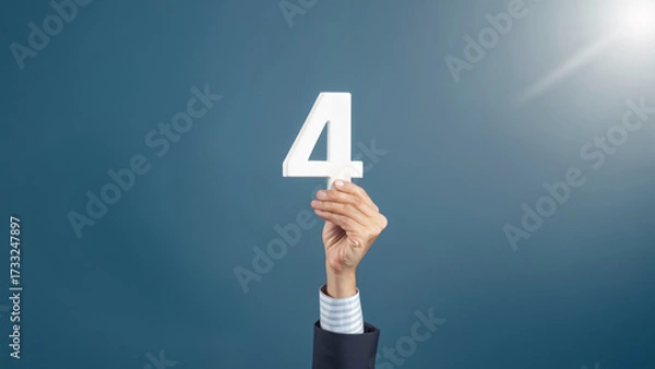 Fototapeta Hand holding number four sign day workweek business concept with hand raised in suit celebrating achievement and positive emotion