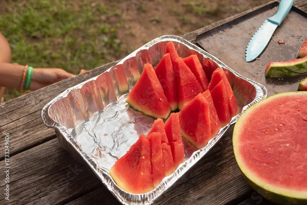 Fototapeta Tray of half-eaten watermelon slices on picnic table at summer family cookout
