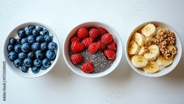 Fototapeta Three bowls blueberries, raspberries, bananas, and walnuts