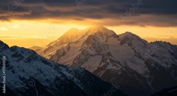 Fototapeta Snowcapped mountains at golden hour with sunburst effect