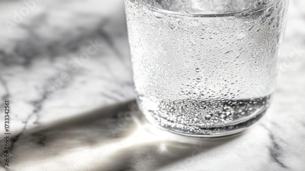Obraz condensation. A close-up of a clear water glass with condensation on a sleek marble surface, reflecting light in a minimalist setting. bar promotions.