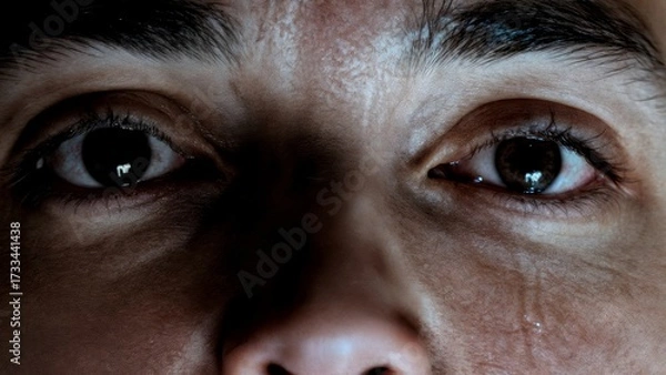 Fototapeta A person's face partially obscured by shadow, with a single tear. Regret, guilt, criminal, consequences, legal.