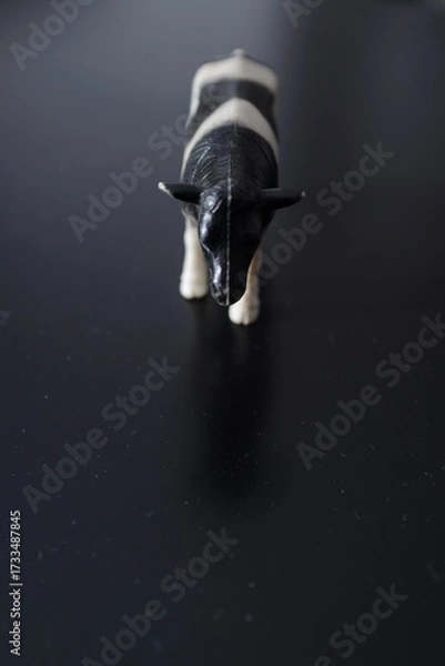 Obraz A miniature figure of a domestic black and white cow that irresistibly reminds of the village and childhood and the taste of fresh domestic milk