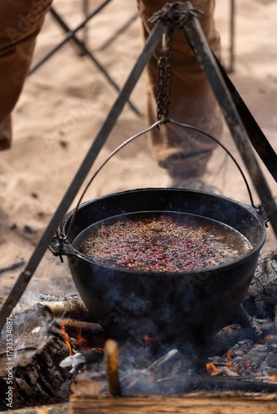 Obraz Cooking at the campsite, adding a spice mixture to the cauldron
