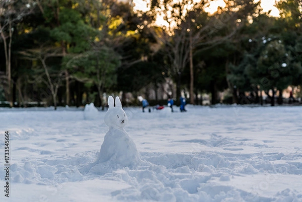 Obraz 公園に雪が積もった日に作られたウサギっぽい雪だるまと夕暮れ