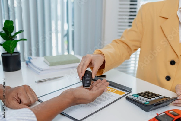Fototapeta A businesswoman in a yellow suit is consulting with a male client about car purchase contracts, showing documents and car models on the desk to finalize agreement and transaction.
