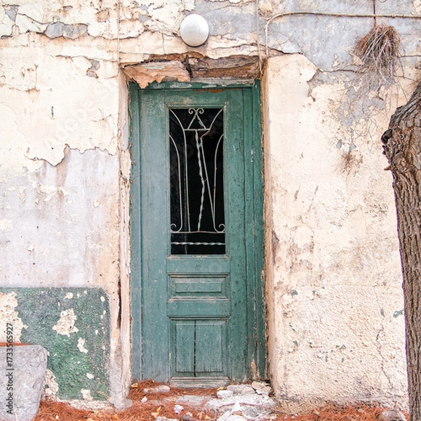 Fototapeta An old, abandoned house green painted wooden door with iron cast railings on worn walls. A different kind of travel to Athens, Greece.