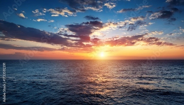 Fototapeta A Beautiful Sunset Over The Ocean With A Few Clouds In The Sky