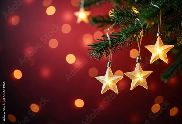 Fototapeta Christmas lights. Golden stars string hanging at fir branches in red defocused background. Holiday card. Copy space for text.