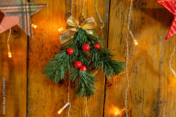 Fototapeta A sprig of a Christmas tree with red berries and a golden bow